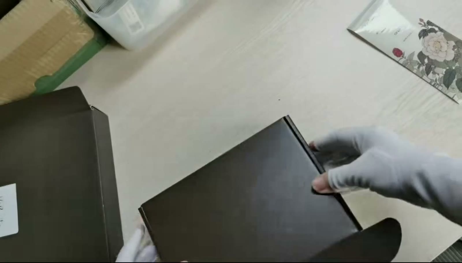 White-gloved hands packing a Sterling Arc order — branded box, botanical tissue, and a thank-you seal.