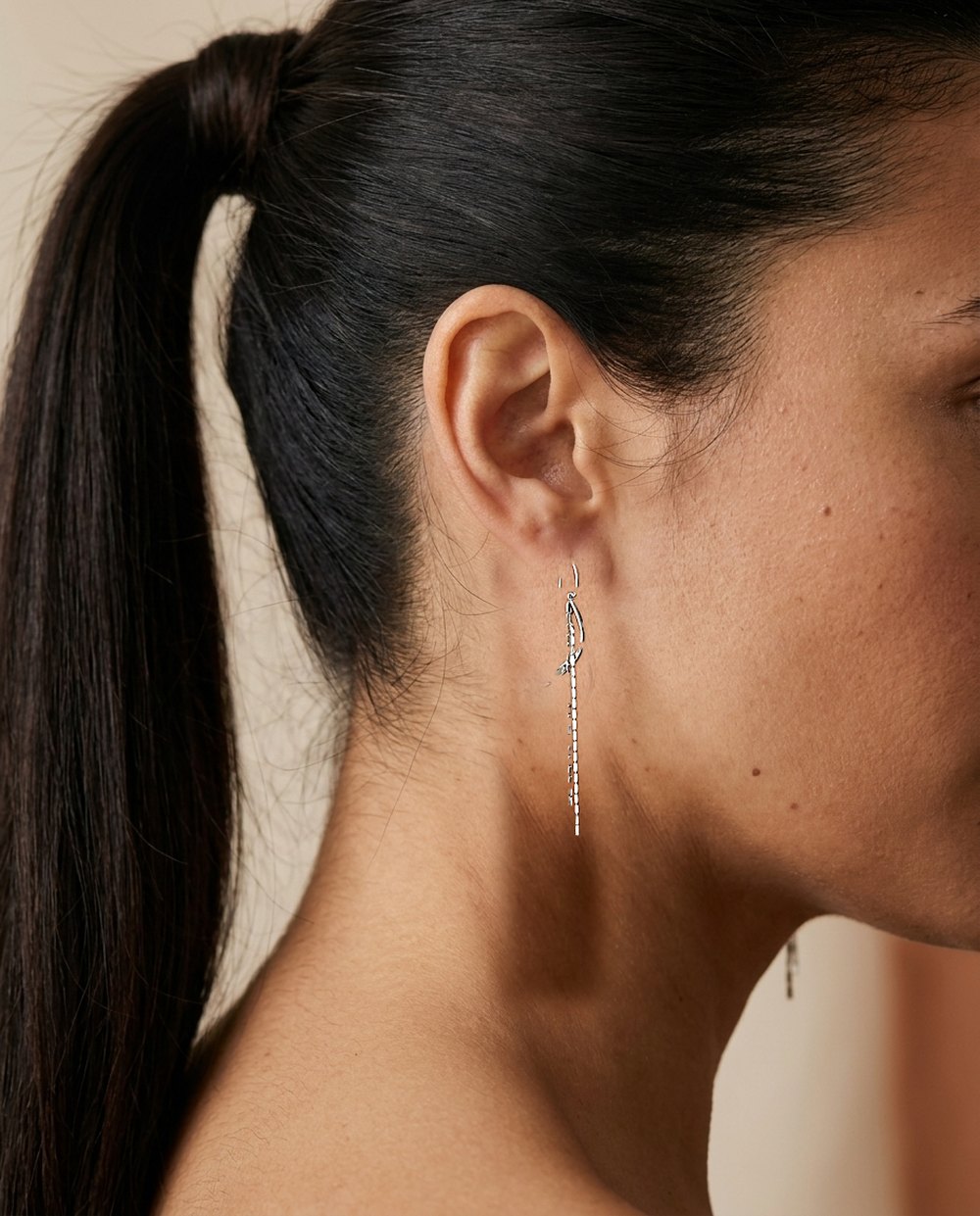 A high ponytail seen from the side, worn with sterling silver tassel drop earrings that are fully visible from behind
